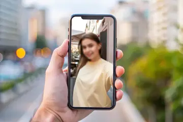 Chcesz wiedzieć, jak zamazać twarz na zdjęciu iPhone? Na ekranie telefonu widać rozmazaną twarz młodej kobiety.