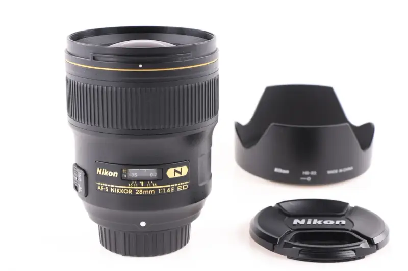 Obiektyw AF-S NIKKOR 28mm 1:1.4E ED z osłoną przeciwsłoneczną i deklem. Jasne oznaczenia obiektywów Nikon.