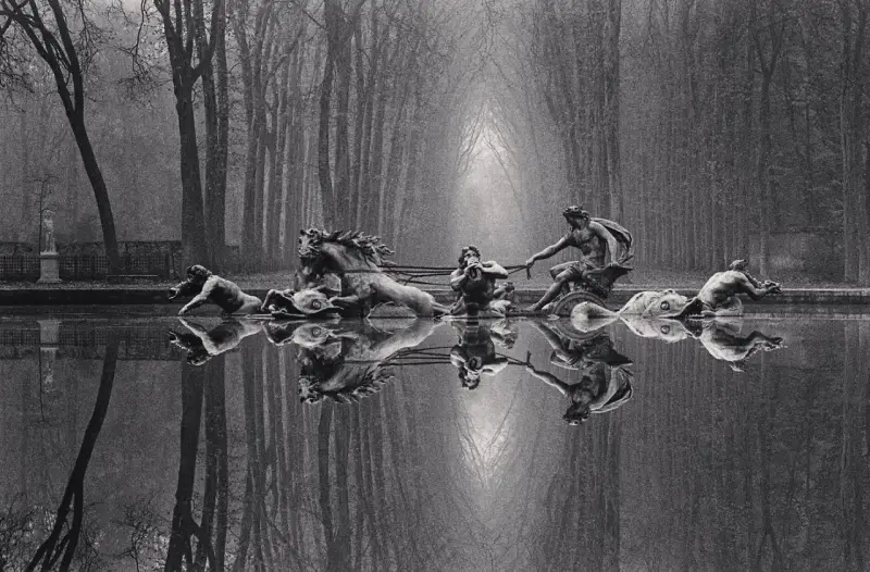 Rzeźby w stawie, koń i ludzie, odbijają się w wodzie. Styl Michael Kenna.